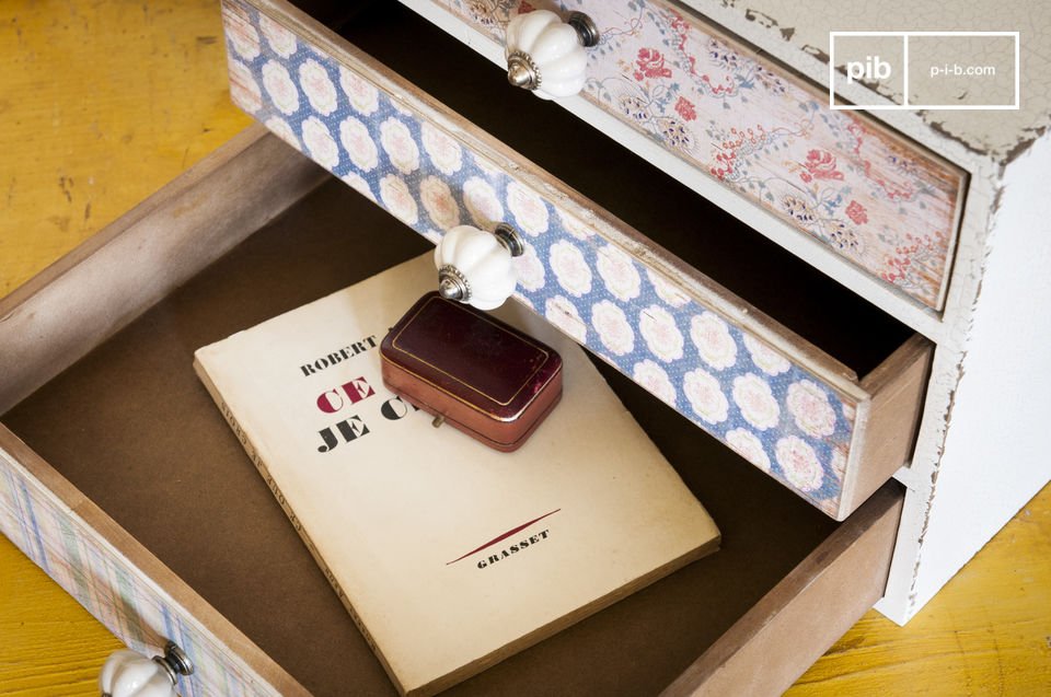 Ce petit meuble rassemble trois tiroirs recouverts de papiers peints d\'inspiration florale qui