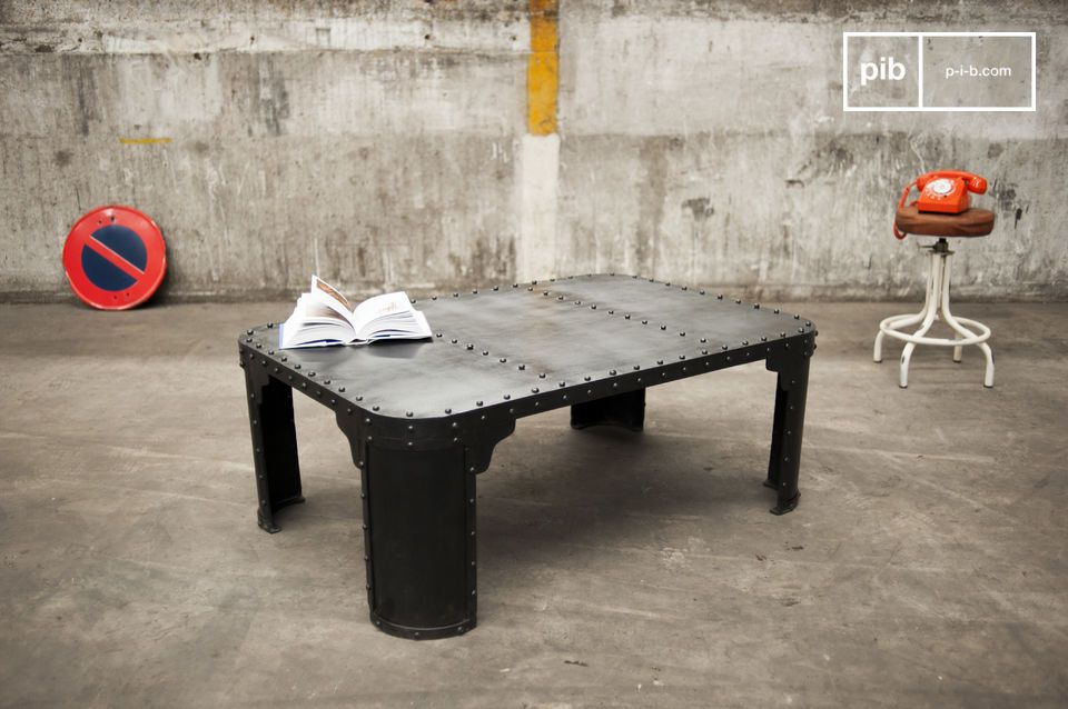 Belle table basse en acier sombre aux rivets apparents.