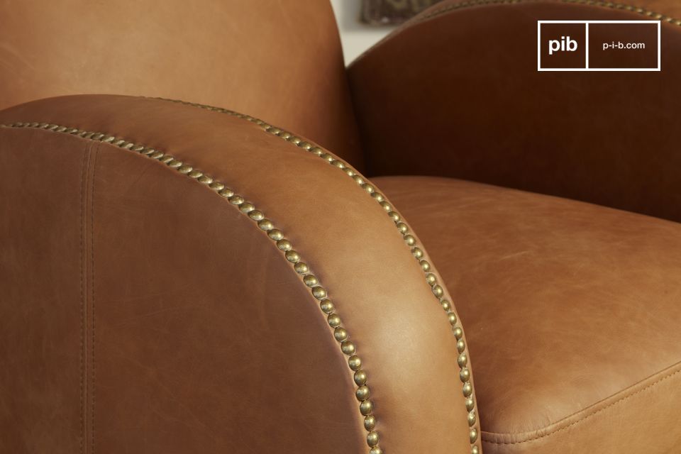 Les tons camel du fauteuil sont sublimés par un travail de cloutage en laiton brossé.