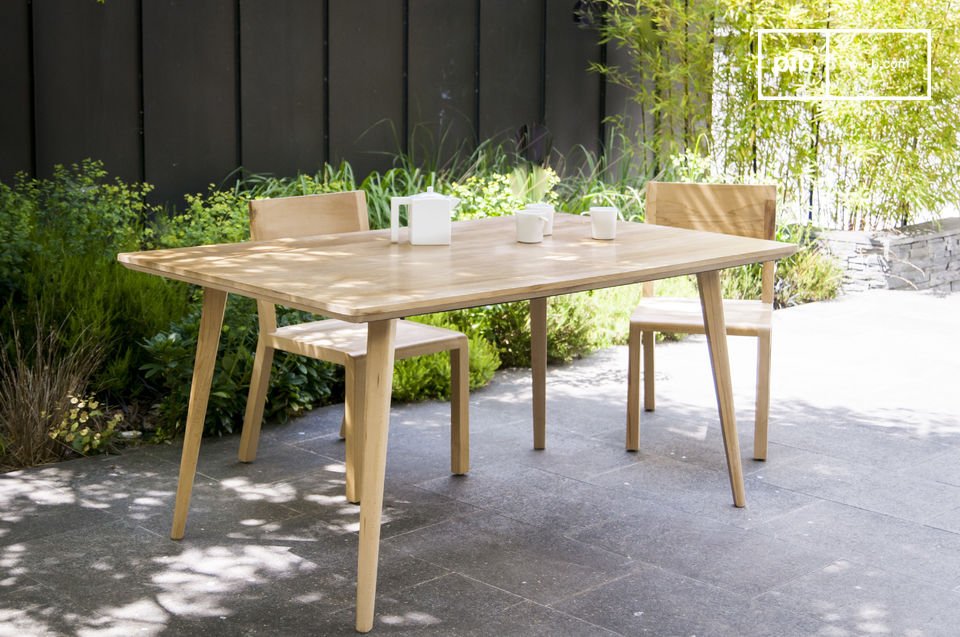 La table a un joli rebord biseauté et des pieds en compas.