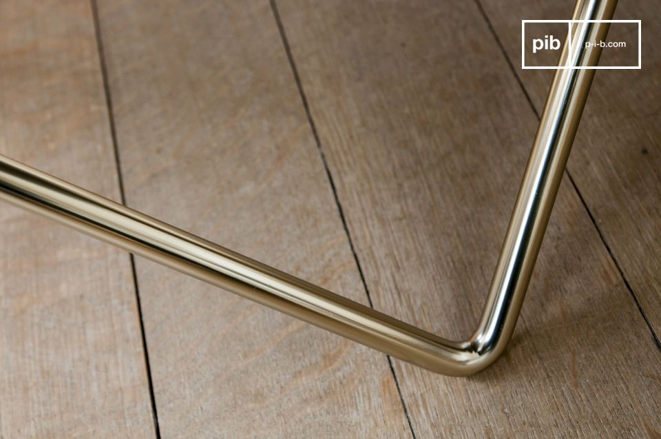 Le fin piètement tubulaire en métal doré affirme le style de la table.