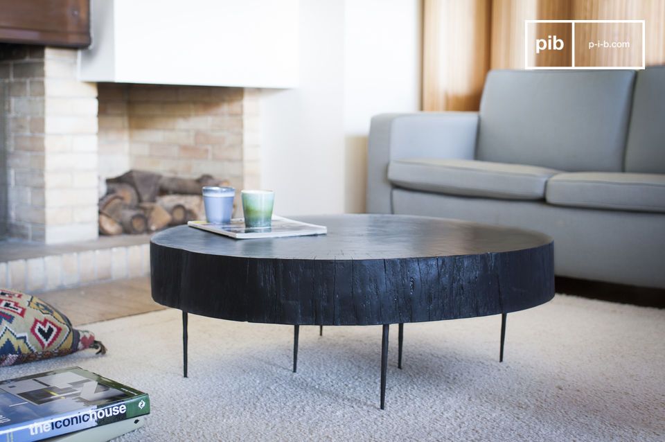 Épaisse table en bois noir aux pieds fins métalliques.