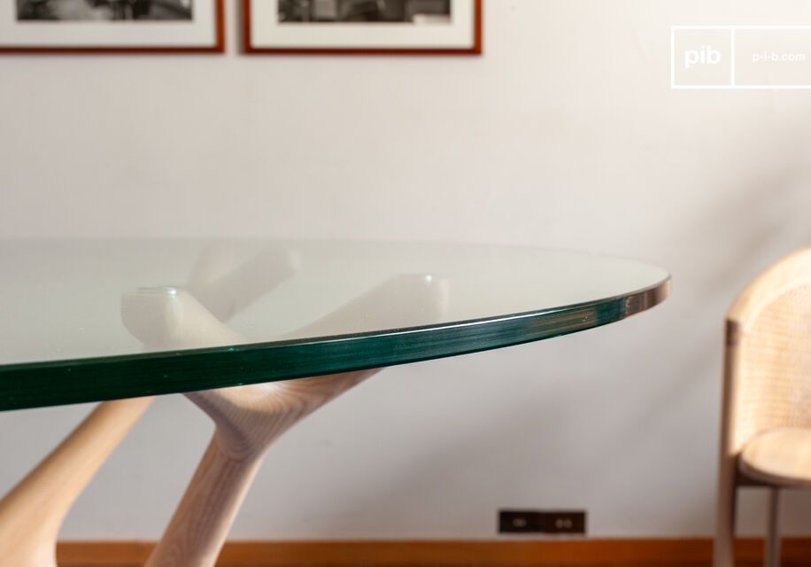 Le plateau circulaire en verre trempé d'1.2cm d'épaisseur laisse voir le dessin organique du  pied en bois massif