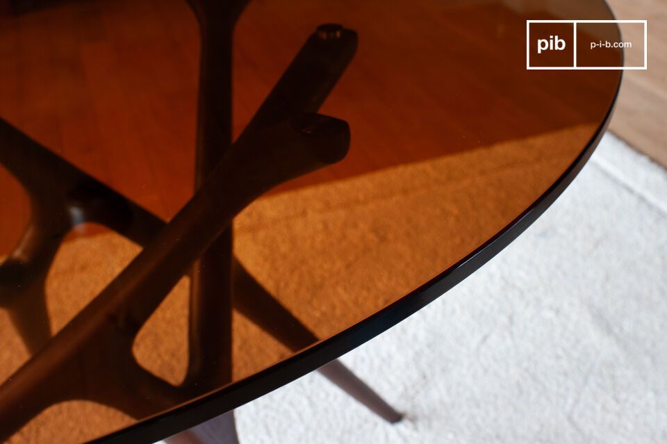 Son plateau en verre fumé repose sur un piètement sculptural évoquant des lignes naturelles