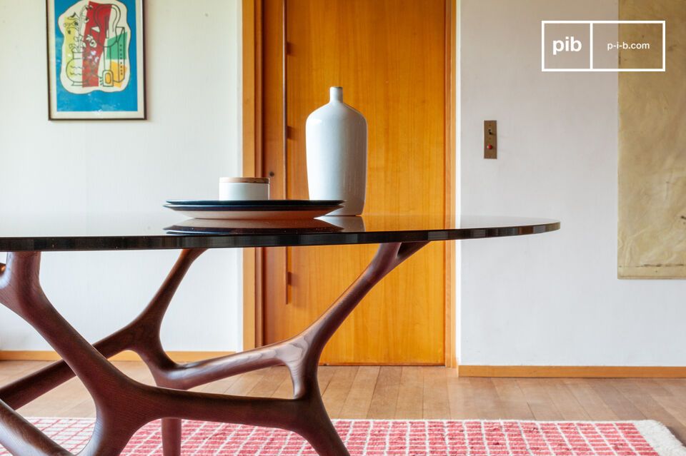 Son plateau en verre fumé et son piètement sculpté inspiré de branches entrelacées lui