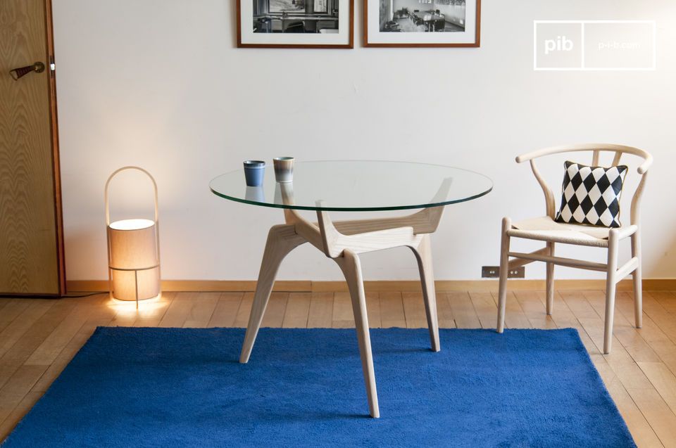 Élégante table avec un plateau en verre et un piétement en frêne.