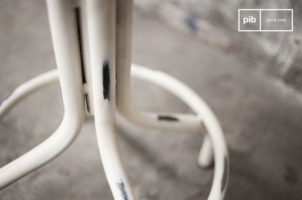 Le tabouret dispose d'un pied blanc patiné tout en courbes.