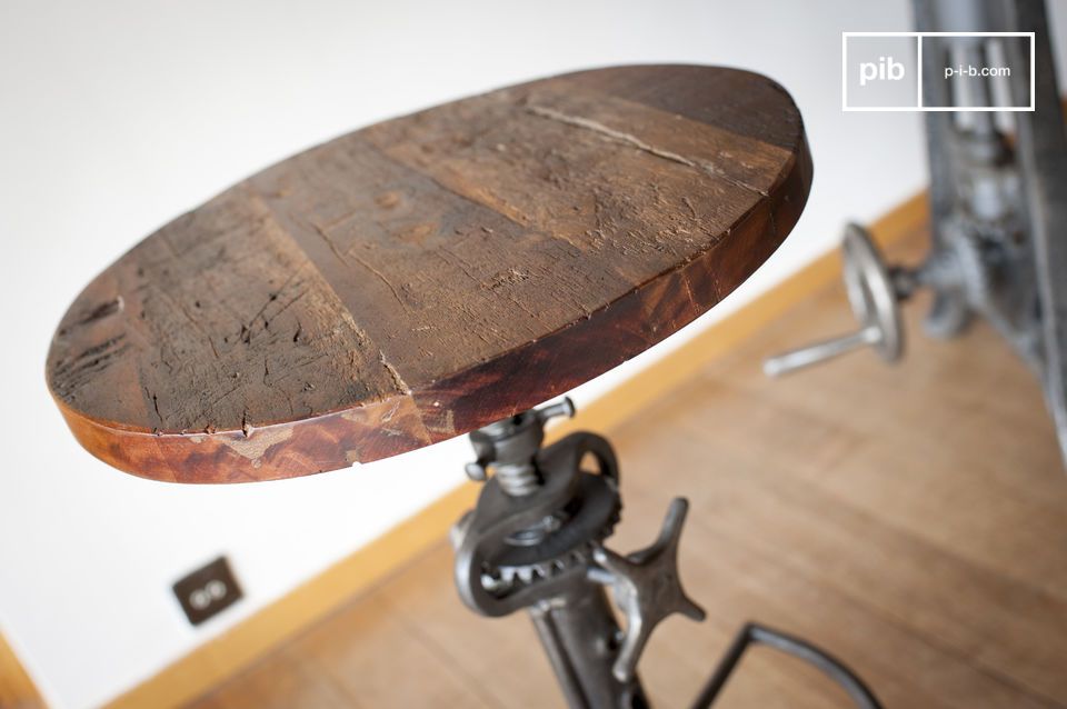 Le tabouret possède un plateau rond en teck ancien verni.